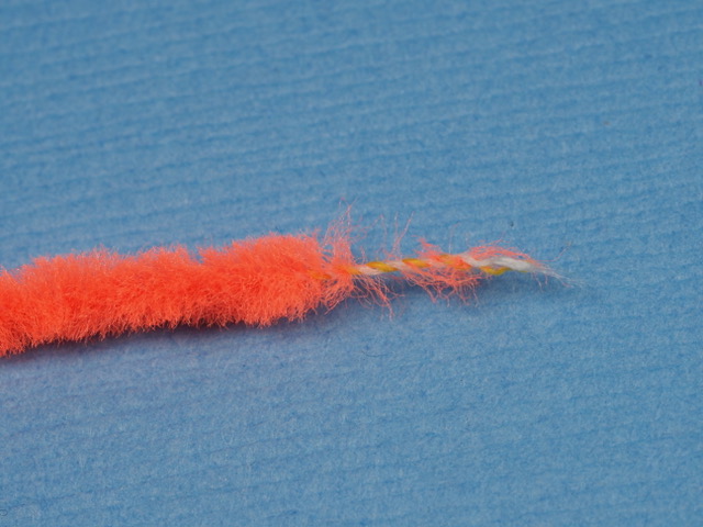 This photo shows how I have styripped off the fuzz of thge chenille for 1/2m inch, exposing the thread core. Securing  the core of the chenille with touching wraps of thread is superior to winding over the intact chenille, because it will not create a lump on the body where the chenille is tied on.