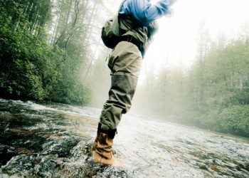 man standing in a river fly fishing